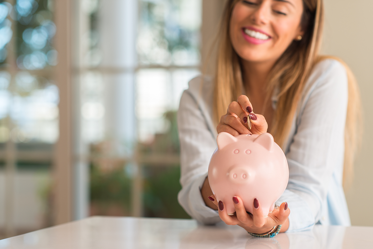 Woman putting coins into a piggy bank